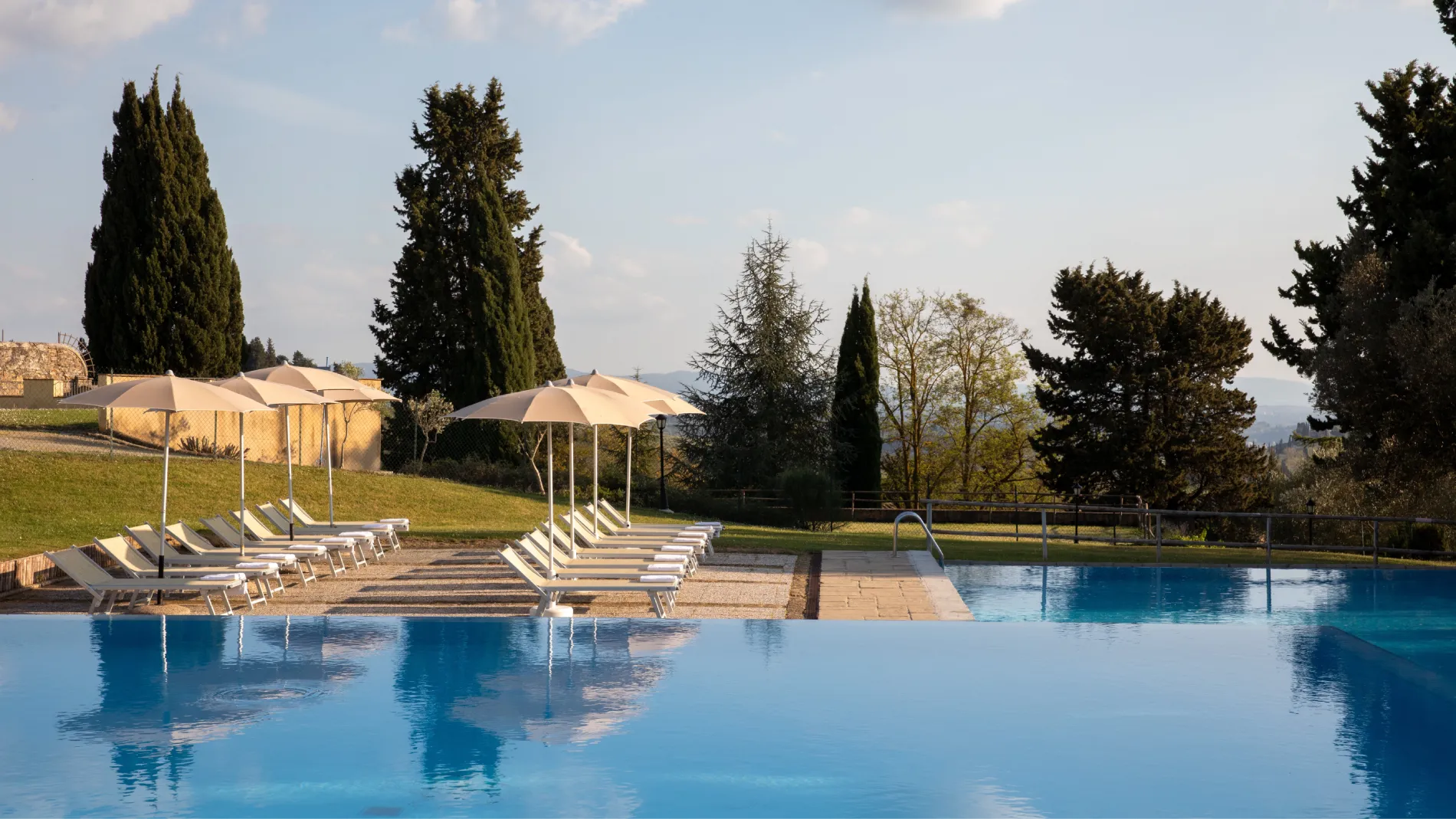 Outdoor pool with loungers and umbrellas set among the rolling hills of Barberino Tavarnelle - Villa San Filippo, BZAR hotels in Tuscany