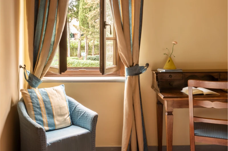 Detail of classic room with armchair and desk near window in Tuscan setting at Barberino Tavarnelle - Villa San Filippo, BZAR hotels in Tuscany